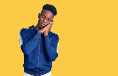 Afro-Amerikalı genç adam spor kıyafetleri giyer, uyur, uyur, hayal kurar, elleriyle poz verir ve gözleri kapalı gülümserdi.. 