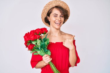 Şapkalı genç İspanyol kadın elinde çiçekler, mutlu ve pozitif gülümsüyor, başparmağıyla mükemmel ve onay işareti yapıyor. 