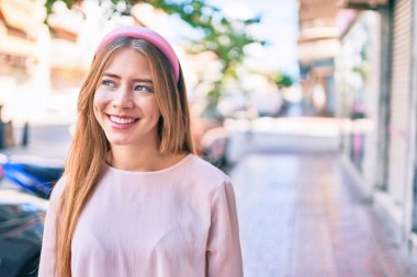 Genç beyaz kız gülümseyerek şehirde mutlu mesut yürüyor..