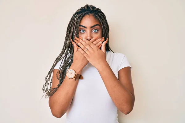 カジュアルな白いTシャツを着た若いアフリカ系アメリカ人の女性がミスのために手で口をカバーショックを受けた 秘密の概念 — ストック写真