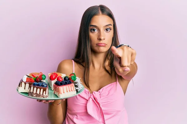 Junge Hispanische Frau Hält Teller Mit Käsekuchen Und Zeigt Mit — Stockfoto