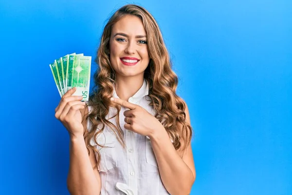 Joven Chica Rubia Sosteniendo Billetes Noruegos Sonriendo Feliz Señalando Con — Foto de Stock