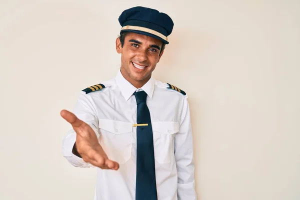 Junger Hispanischer Mann Flugzeugpilotenuniform Lächelt Fröhlich Und Bietet Mit Der — Stockfoto