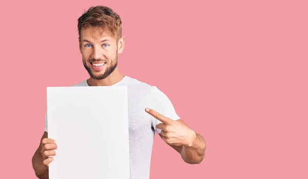 Joven Hombre Caucásico Sosteniendo Banner Vacío Sonriendo Feliz Señalando Con —  Fotos de Stock