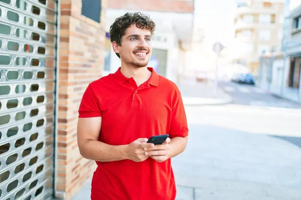 Mladý Pohledný Kavkazský Muž Usměvavý Šťastný Pomocí Smartphone Chůze Městě — Stock fotografie