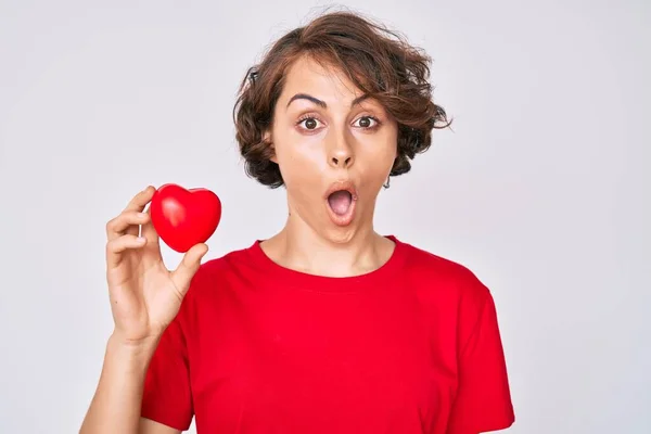 Mujer Hispana Joven Sosteniendo Corazón Asustada Asombrada Con Boca Abierta — Foto de Stock