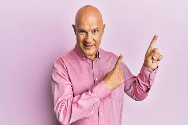 분홍색 셔츠를 웃으며 손가락으로 가리키는 카메라를 중년의 대머리 — 스톡 사진