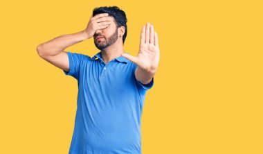 Latin kökenli genç bir adam, günlük kıyafetler giyip, elleriyle gözlerini kapatıyor ve üzgün ve korku ifadeleriyle jestleri durduruyor. utangaç ve olumsuz kavram. 