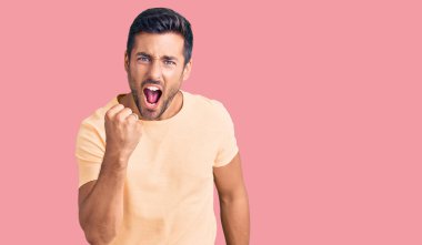 Latin asıllı genç bir adam, kızgın ve kızgın. Öfkeyle bağırırken yumruğunu sallıyor ve öfkeleniyor. öfke ve agresif konsept. 