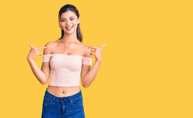 Gündelik kıyafetler giyen, kendine güvenen, gülümseyen, kendini gururlu ve mutlu gösteren genç ve güzel bir kadın.. 