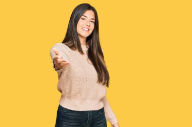 Genç esmer kadın, sıradan bir kazak giyiyor. Gülümsüyor. Avuç içi dolusu yardım eli uzatıyor ve kabulleniyor.. 