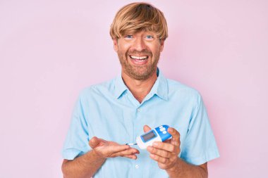 Glikoz ölçer kullanan genç sarışın adam kahkahalarla gülüyor.. 