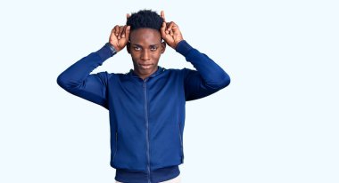 Genç Afro-Amerikan erkek spor giyer komik jestler yapar parmakları kafasının üstünde boğa boynuzu gibi 