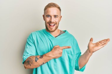 Gündelik giysiler giyen genç beyaz adam kameraya hayret ediyor ve gülümsüyor.. 