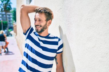 Sakallı yakışıklı beyaz adam, dışarıda mutlu bir şekilde gülümsüyor.