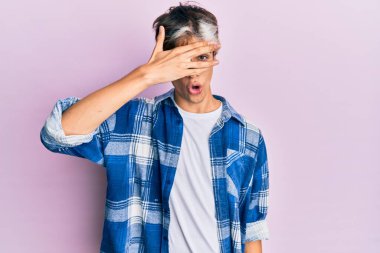 Gündelik kıyafetler giyen genç İspanyol adam şok içinde yüzünü ve gözlerini kapayarak utanmış ifadesiyle parmaklarından bakıyor.. 