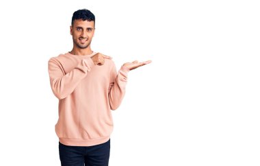 Gündelik kıyafetler giyen genç İspanyol adam kameraya hayret ediyor ve gülümsüyor.. 