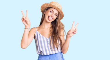 Genç, sarışın, yaz şapkası takan, ağzı açık gülümseyen, iki elini de zafer işareti yapan güzel bir kadın. İki numara.. 