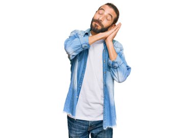 Uzun saçlı, sakallı, sıradan bir kot ceket giyen, yorgun uyuyan, hayal kuran, elleri ve gözleri kapalı gülümseyen çekici bir adam.. 