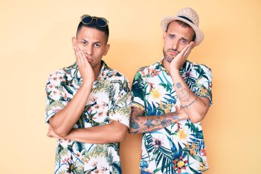 Yazlık şapka ve Hawaii tişörtü giyen iki genç eşcinsel kollarını kavuşturup depresyondan sıkılmış ve yorgun görünüyor.. 