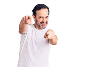 Orta yaşlı yakışıklı bir adam günlük tişörtler giyip seni ve kamerayı işaret ediyor. 