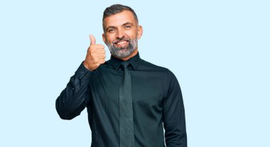 Orta yaşlı, iş elbiseleri giyen, mutlu ve pozitif gülümseyen, mükemmel ve onay işareti yapan yakışıklı bir adam. 