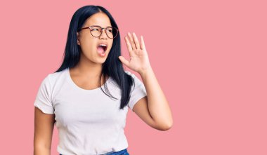 Genç, güzel Asyalı bir kız, günlük kıyafetler ve gözlük takmış el ele tutuşmuş bağırıyor ve çığlık çığlığa bağırıyor. iletişim konsepti. 