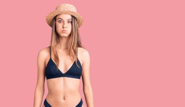 Bikini giyen, şapkalı, komik yüzlü güzel bir kız. Havayla şişmiş ağız, çılgın bir ifade.. 