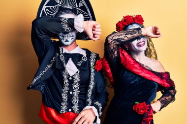 Genç çift, Meksika 'da ölü kostümünü giyip sarı gözleri kapayarak neşeli ve komik bir şekilde gülümsüyor. kör kavram. 