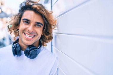 Şehrin duvarına dayanmış, kulaklık takan yakışıklı İspanyol bir adam.