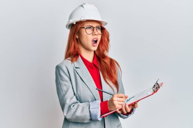 Genç, kızıl saçlı, mimar şapkalı kızgın ve kızgın bir çığlık atan sinirli ve öfkeli bir kadın. Öfkeyle bağırıyor. öfke ve agresif konsept. 