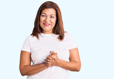 Güzel, orta yaşlı, sıradan kıyafetler giyen mutlu ve pozitif gülümseyen, neşeli ve kendinden emin bir kadın.