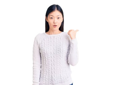 Gündelik süveter giyen genç ve güzel bir Çinli kadın el ile işaret ederek şaşırdı, ağzı açık hayret içinde kaldı.. 