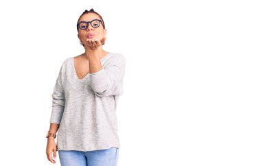 Gündelik giysiler giymiş genç Latin bir kadın kameraya bakıp havada bir öpücük savuruyor ve sevimli ve seksi oluyor. aşk ifadesi. 