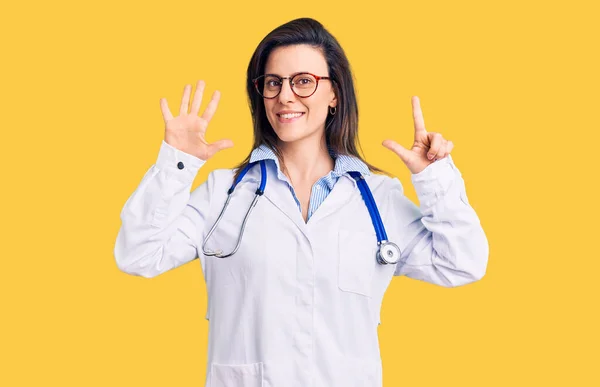 年轻美丽的女人 戴着医生听诊器和眼镜 用七号手指显示和指尖 面带微笑 自信而快乐 — 图库照片