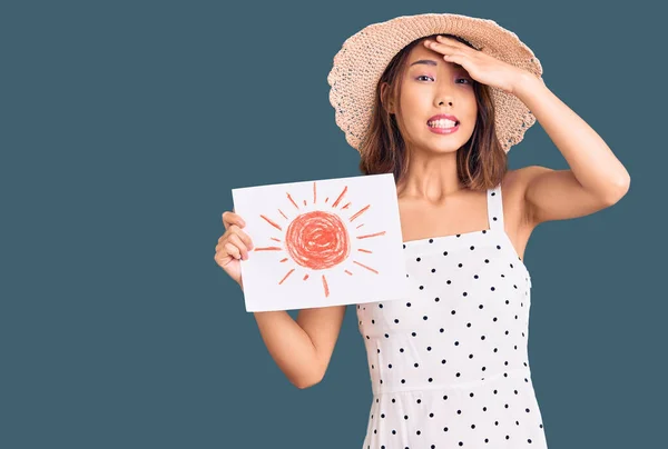 Young beautiful chinese girl wearing summer hat holding sun draw stressed and frustrated with hand on head, surprised and angry face