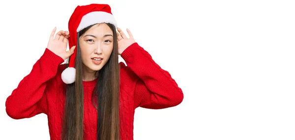 Jovem Chinesa Usando Chapéu Natal Tentando Ouvir Ambas Mãos Gesto — Fotografia de Stock