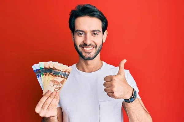 Ung Latinamerikansk Man Håller Kanadensiska Dollar Ler Glad Och Positiv — Stockfoto