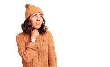 Genç, güzel, melez, yün kazak giyen, şapkalı, boynu ağrıyan, boğazı ağrıyan, grip, mantar ve enfeksiyon kapmış bir kadın. 