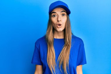 Piercing 'li, teslimat üniformalı, şapkalı genç esmer kadın kameraya hayret ediyor ve gülümsüyor.. 