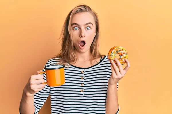 Hermosa Mujer Rubia Comiendo Donut Bebiendo Café Asustada Sorprendida Con —  Fotos de Stock