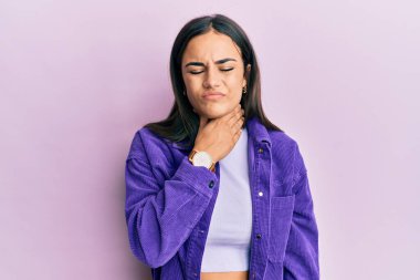 Genç esmer kadın gündelik giysiler giyiyor. Ağrılı boyuna dokunuyor. Grip, mantar ve enfeksiyon yüzünden boğaz ağrısı çekiyor. 