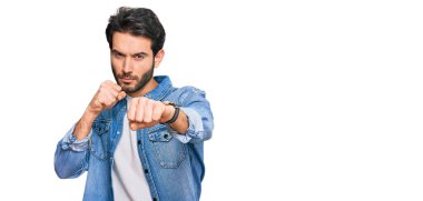 Latin kökenli genç adam gündelik kıyafetler giyiyor. Yumruk yumruğa dövüşüyor, agresif ve öfkeli saldırı, tehdit ve şiddet uyguluyor. 
