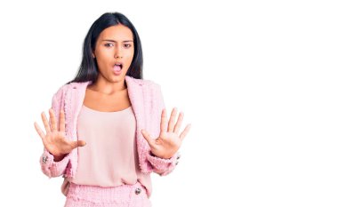 İş kıyafetleri giymiş genç, güzel bir Latin kız. Korkudan dehşete düşmüş ve korkmuş. El hareketlerini bırak, şok içinde bağır. panik konsepti. 