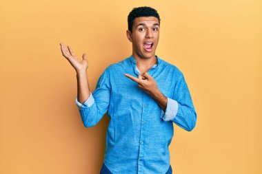 Gündelik giysiler giyen genç Arap adam kameraya hayret ediyor ve gülümsüyor.. 