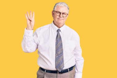 Kıdemli gri saçlı adam, iş kıyafetleri giymiş ve parmaklarını dört numara ile gösterip gülümserken kendinden emin ve mutlu. 