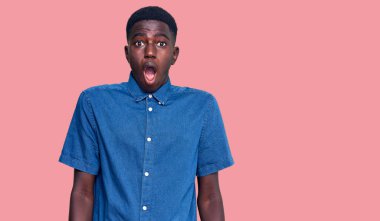 Genç Afro-Amerikan adam günlük giysiler giyiyor. Şaşırmış ve şaşırmış bir ifadeyle, korku ve heyecanlı bir yüzle.. 