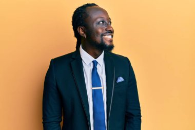 Yakışıklı, takım elbiseli ve kravatlı genç bir adam. Taraf arıyor, rahat bir görünüm takınıyor ve kendine güvenen bir gülümseme takınıyor.. 