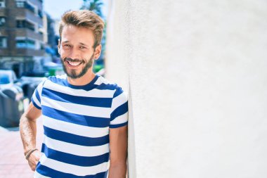 Sakallı yakışıklı beyaz adam, dışarıda mutlu bir şekilde gülümsüyor.