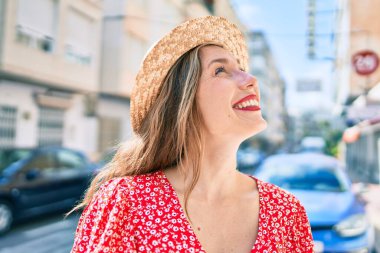 Genç sarışın kadın tatilde gülümsüyor. Mutlu bir şekilde caddede yürüyor.